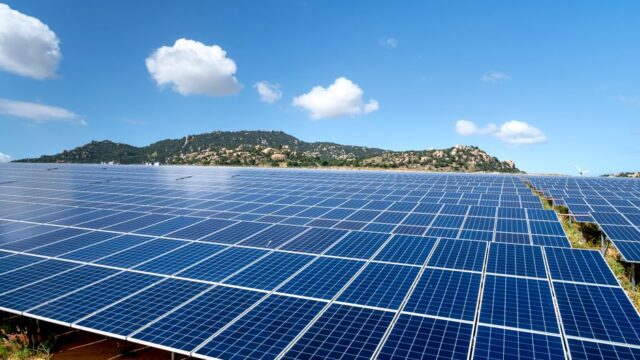 A sprawling solar farm with blue solar panels under a vibrant sky, showcasing renewable energy.
