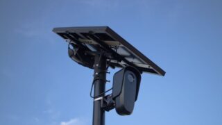 Solar-powered surveillance camera with a clear blue sky backdrop, highlighting modern technology.