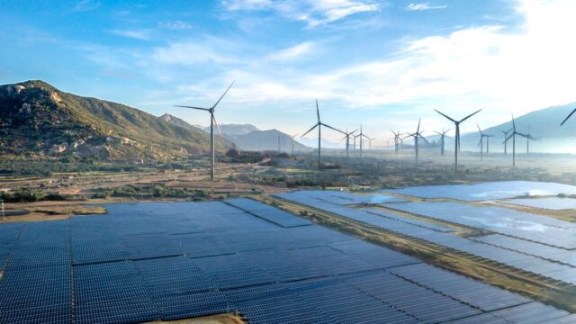 Stunning aerial view of renewable energy sources with wind turbines and solar panels in a mountainous landscape.