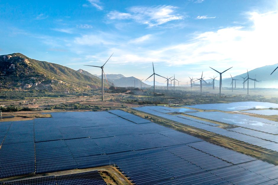 Stunning aerial view of renewable energy sources with wind turbines and solar panels in a mountainous landscape.