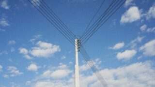 High voltage power lines stretching across a clear blue sky, symbolizing energy distribution.