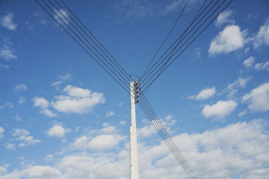 High voltage power lines stretching across a clear blue sky, symbolizing energy distribution.