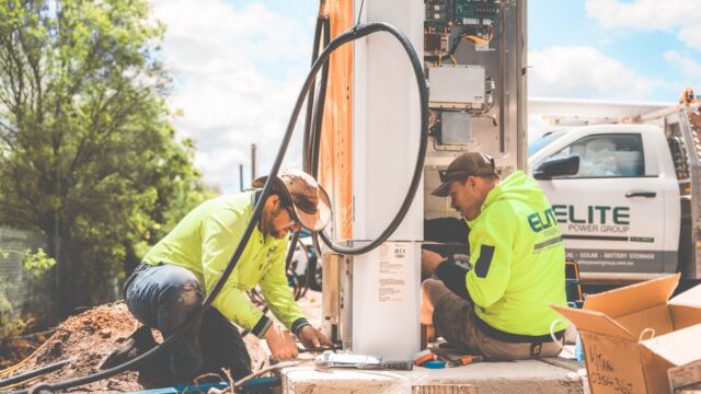 Two electricians working on electrical equipment installation outdoors in Tomago, NSW, Australia.