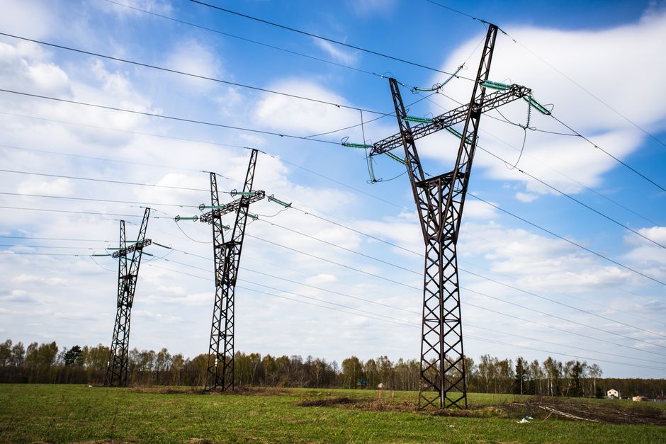 High voltage electric towers stand tall over a clear sky and grassy field, providing a serene landscape view.