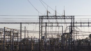 High-voltage electrical substation with steel structures and power lines at dawn.
