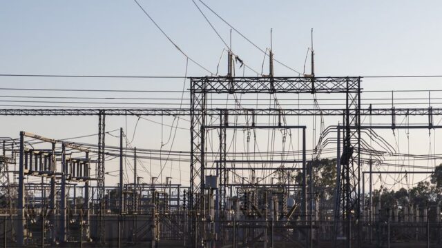 High-voltage electrical substation with steel structures and power lines at dawn.