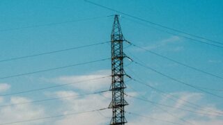 High voltage power lines stretching into blue sky with scattered clouds.