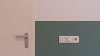Modern interior scene showing a door handle and a power outlet on a two-toned wall.