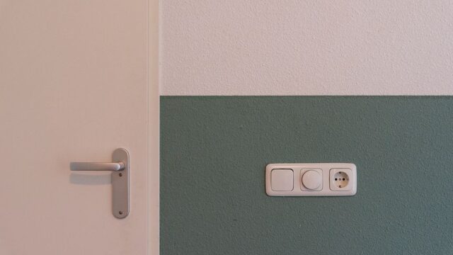 Modern interior scene showing a door handle and a power outlet on a two-toned wall.