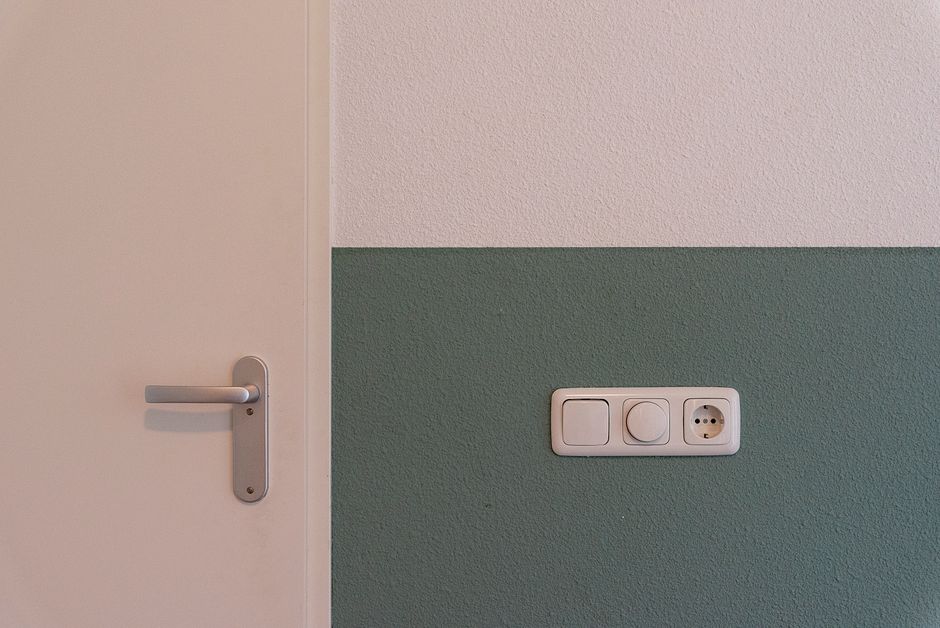 Modern interior scene showing a door handle and a power outlet on a two-toned wall.