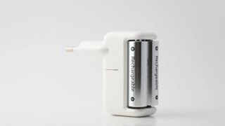 Minimalist shot of a rechargeable battery charger with two batteries on a white backdrop.
