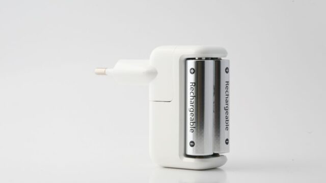 Minimalist shot of a rechargeable battery charger with two batteries on a white backdrop.